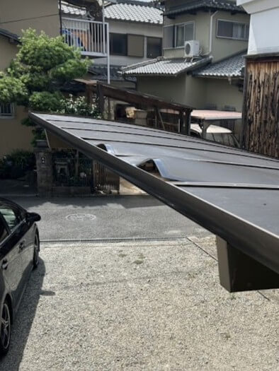 ぶつけられたカーポートの屋根が曲がっている写真